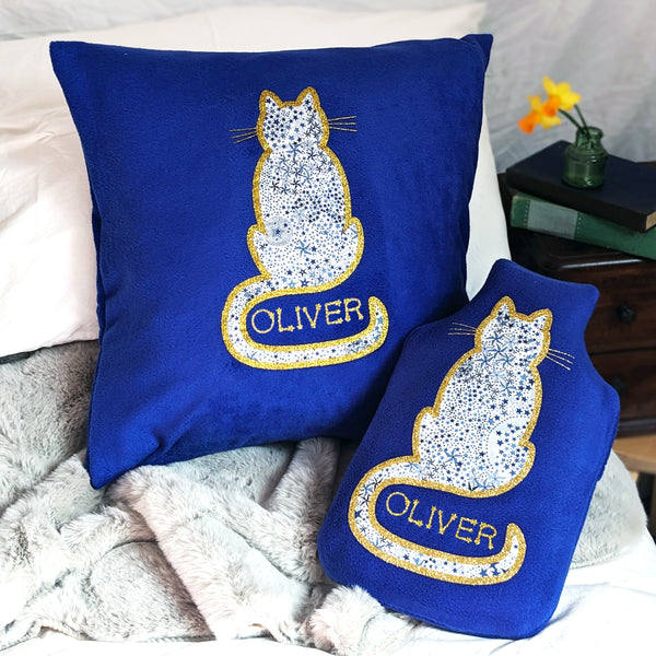 Gift set of royal blue cushion and hot water bottle cover featuring starry Liberty Adelajda fabric cat and gold glitter personalisation.