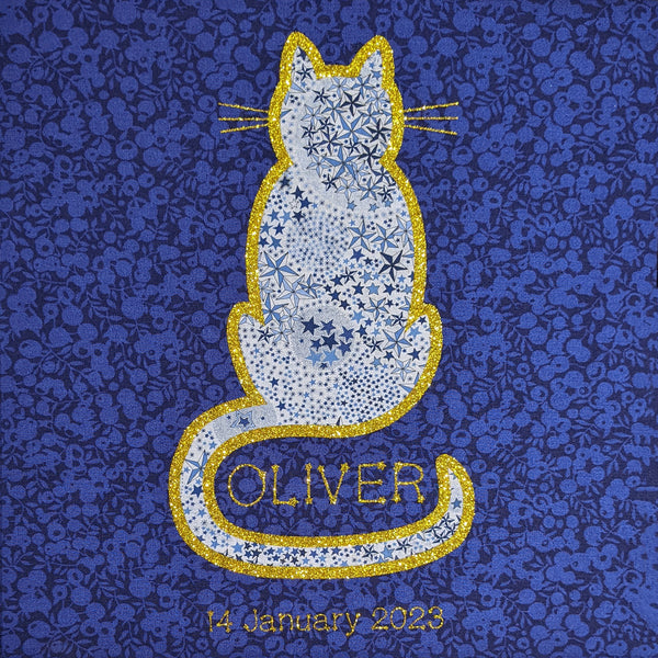Close up of a square print with a starry Liberty fabric cat edged with gold glitter featuring the name in the curve of the tail and date of birth below.