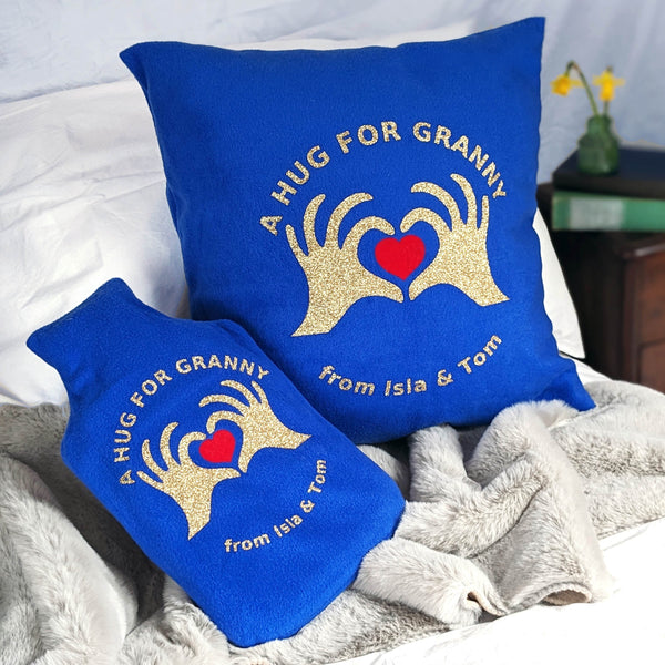 Matching royal blue fleece hot water bottle cover and cushion set featuring gold glitter hands and heart. Peronalised with gold glitter text
