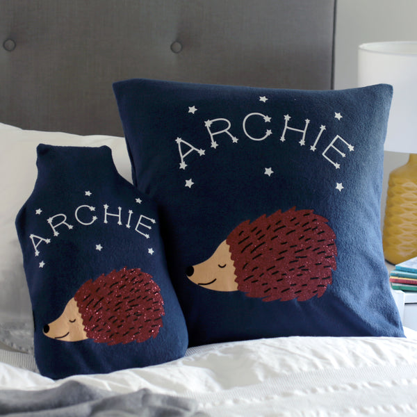Navy fleece cushion and hot water bottle cover set with sparkling hedgehog and personalised with child's name in glow-in-the-dark vinyl with stars.