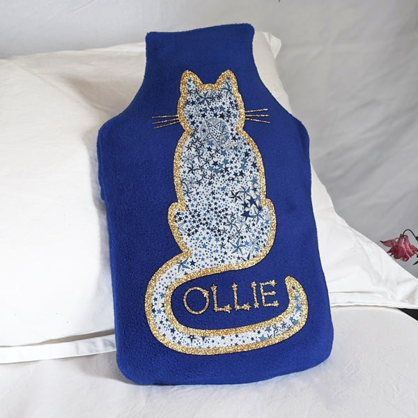 Royal blue hot water bottle cover with Liberty fabric cat with gold glitter details and personalisation.