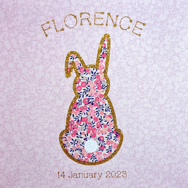 Close up of Liberty fabric rabbit edged with gold glitter featuring name and date of birth. Lovely new baby gift
